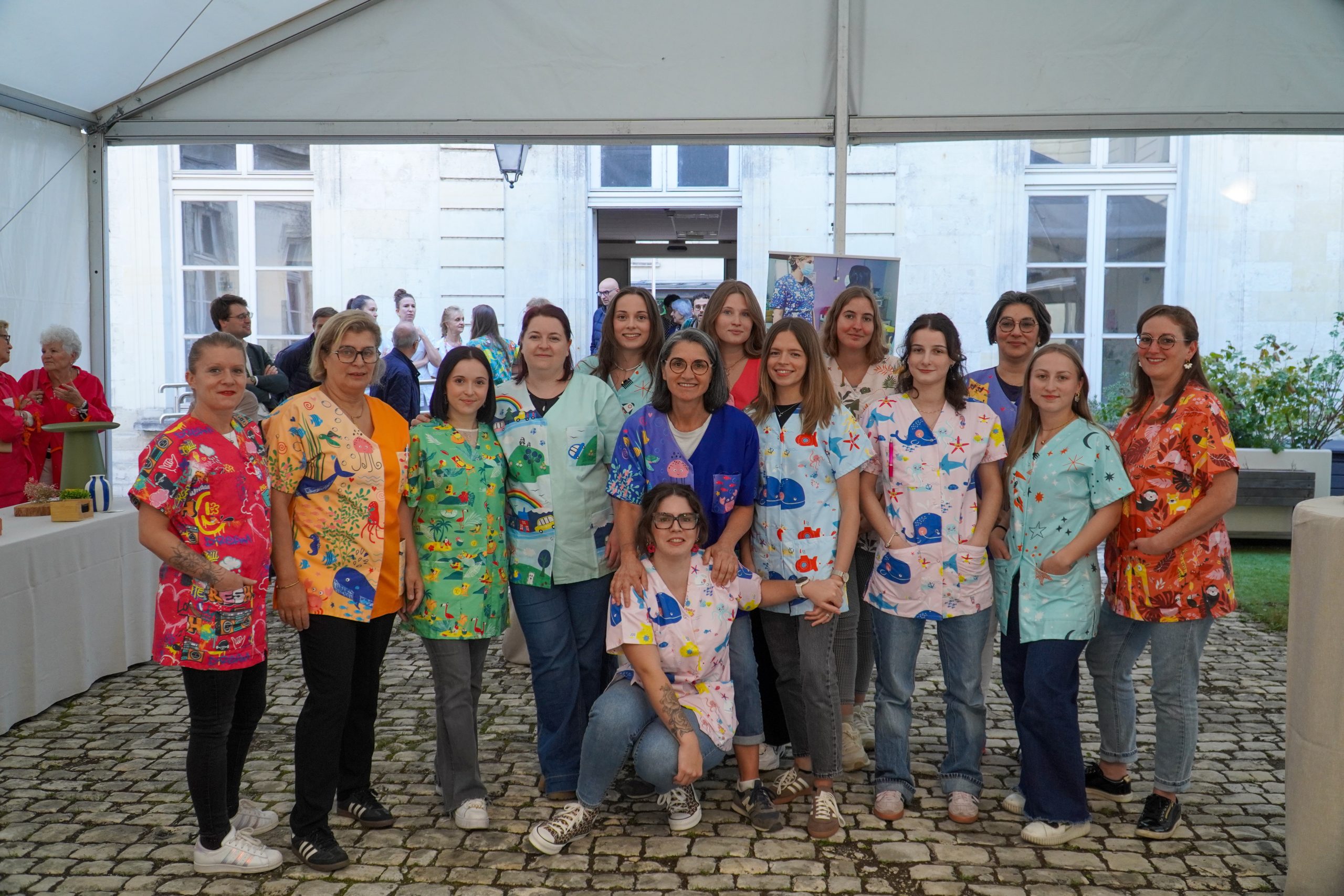 Inauguration extérieure avec des personnes sous une tonnelle discutant. Une table est dressée avec une collation pour les invités